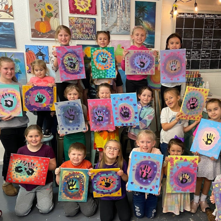 Children holding up their colorful handprint art in a classroom setting.