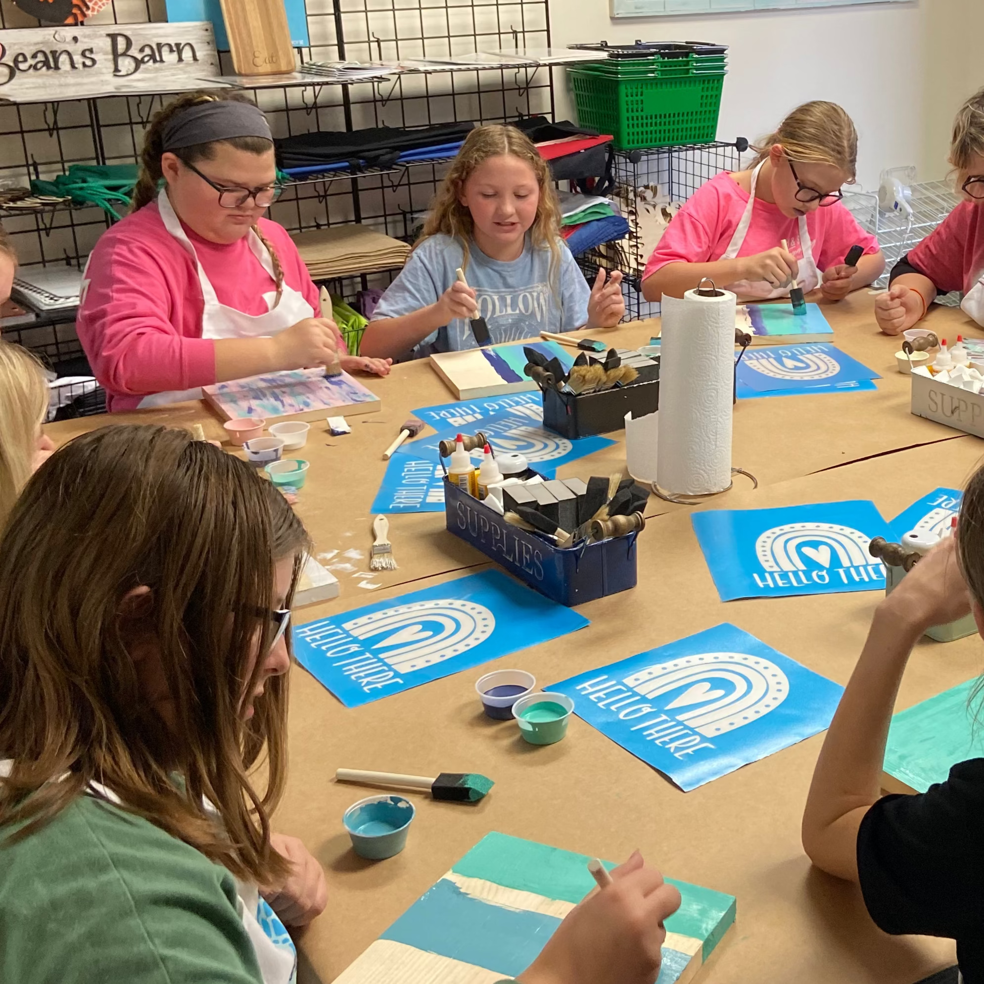 Children working on art projects at a table in a classroom setting.